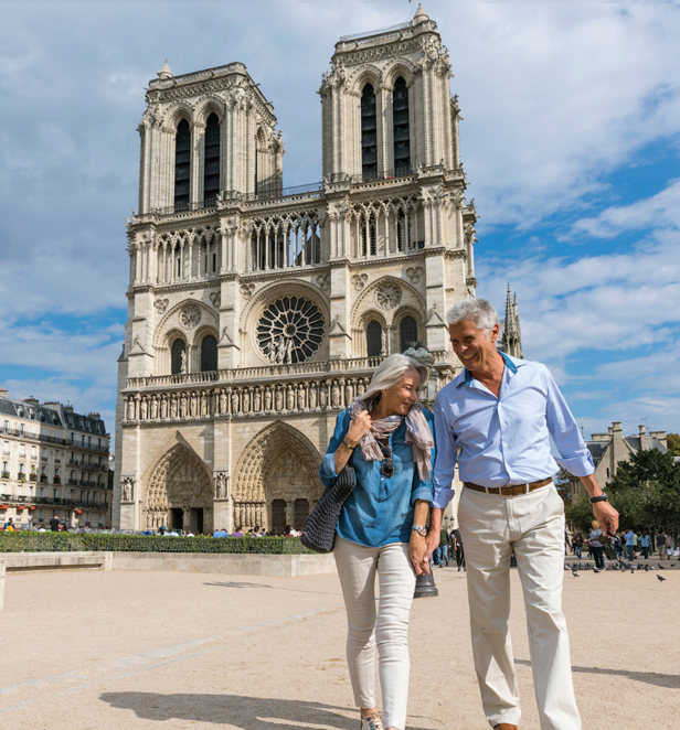 Couple walking holding hands in front of Notre Dame, Paris, France.