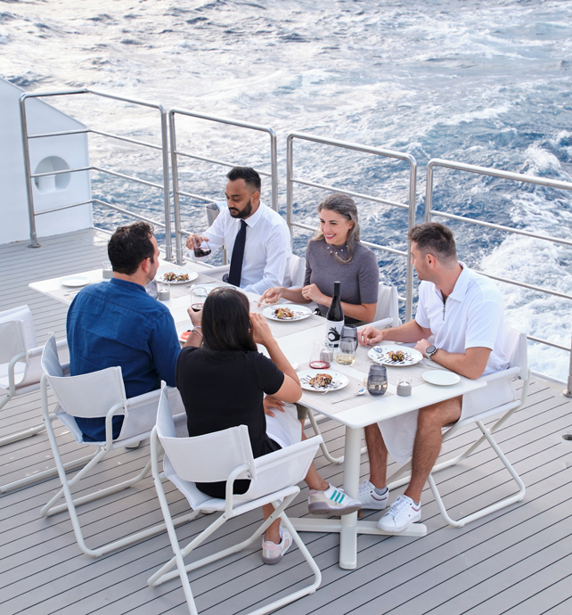 Group of friends dining on deck of Emerald Sakara superyacht in Caribbean