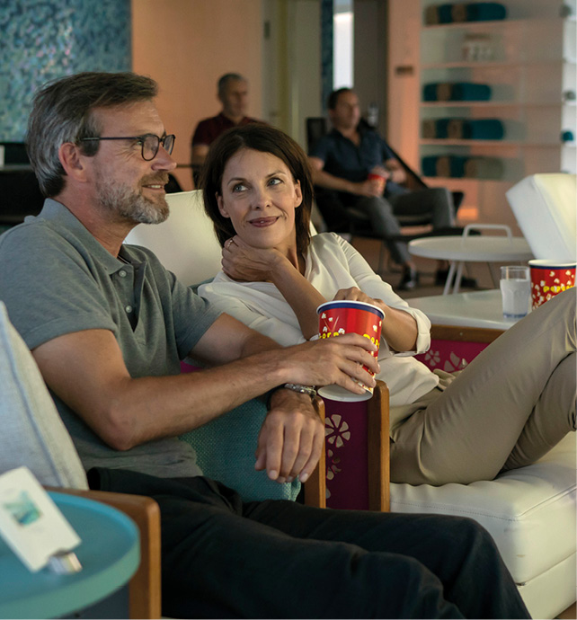 Group of friends watching a film on board a luxury river ship, with a couple sharing a tub of popcorn 