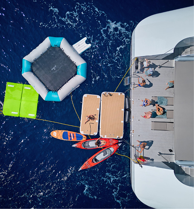 Guests swimming in the sea and enjoying water sports toys from the marina platform at the back of an Emerald Cruises yacht